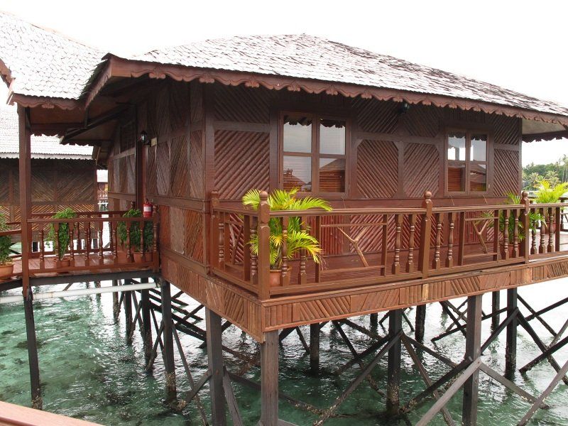 Wooden bungalow on stilts over clear water.