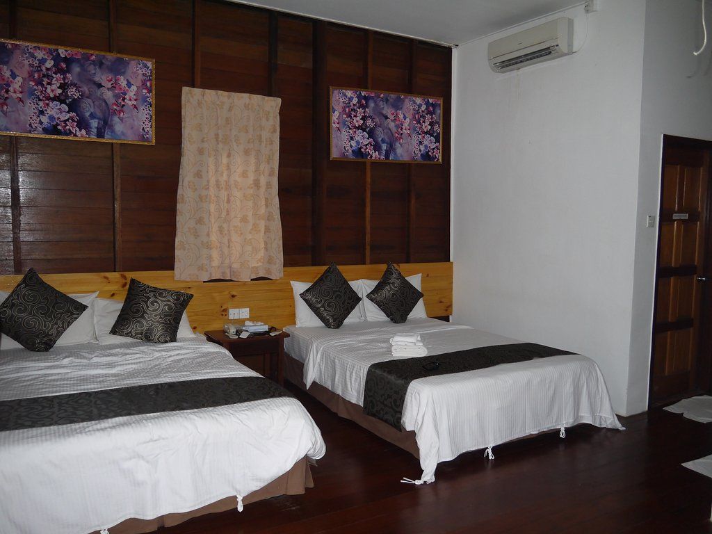 Bedroom with two beds, wooden panel wall, artwork, and air conditioner.