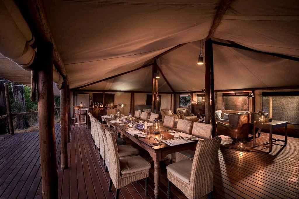 A covered outdoor dining area with a long table set for a meal.
