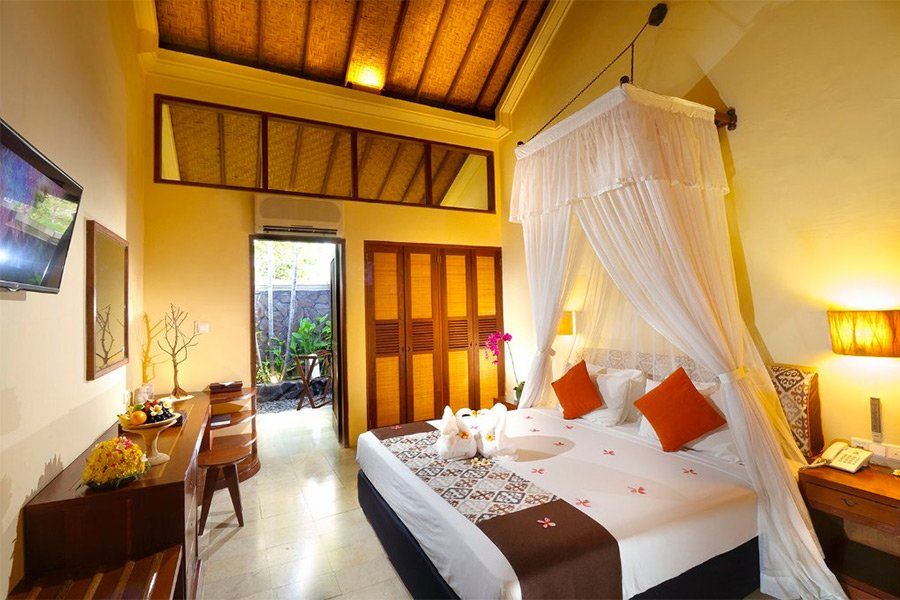 Bedroom with canopy bed, wooden furniture, and doorway leading to a small outdoor area.