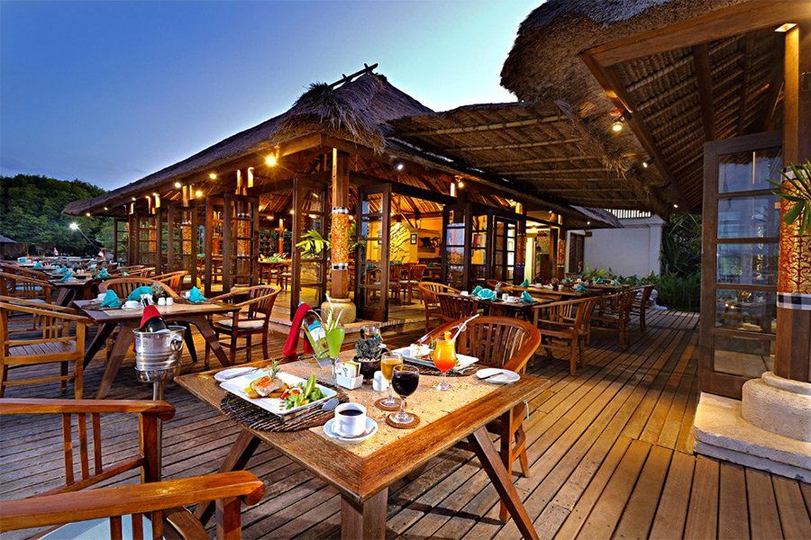 Wooden outdoor restaurant at dusk with tables set and food visible.