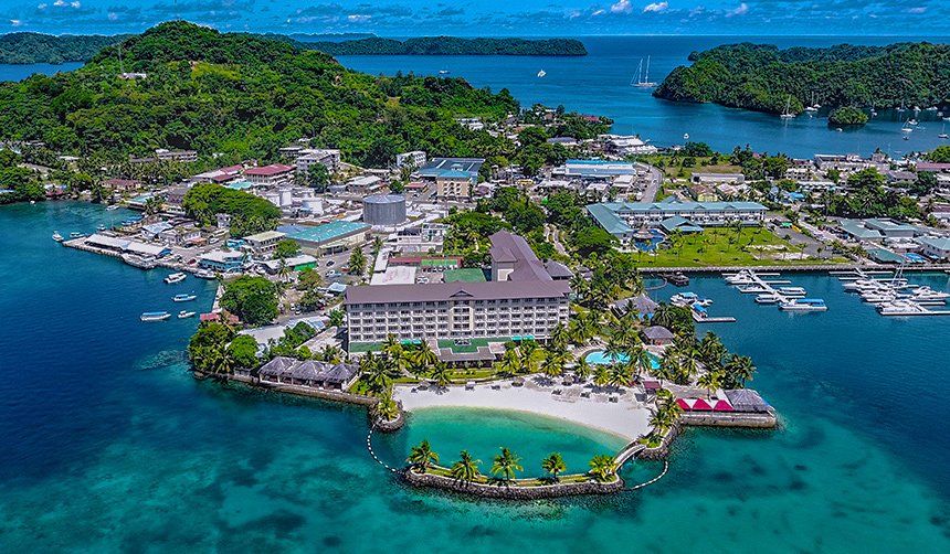 Aerial view of a coastal town with a large hotel on a peninsula, surrounded by blue water.