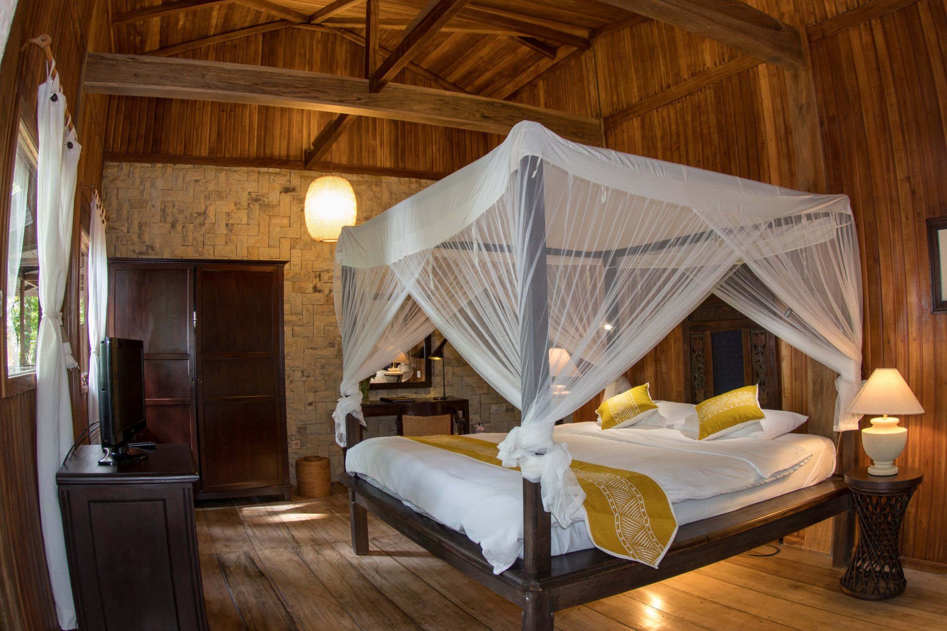 Bedroom with canopy bed, wooden walls, and soft lighting.