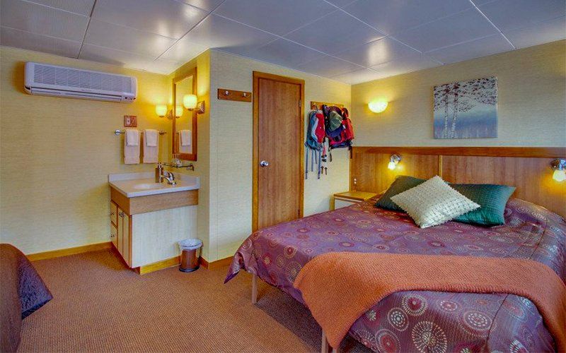 Motel room with double bed, bathroom area, and a second bed visible. Warm color scheme.