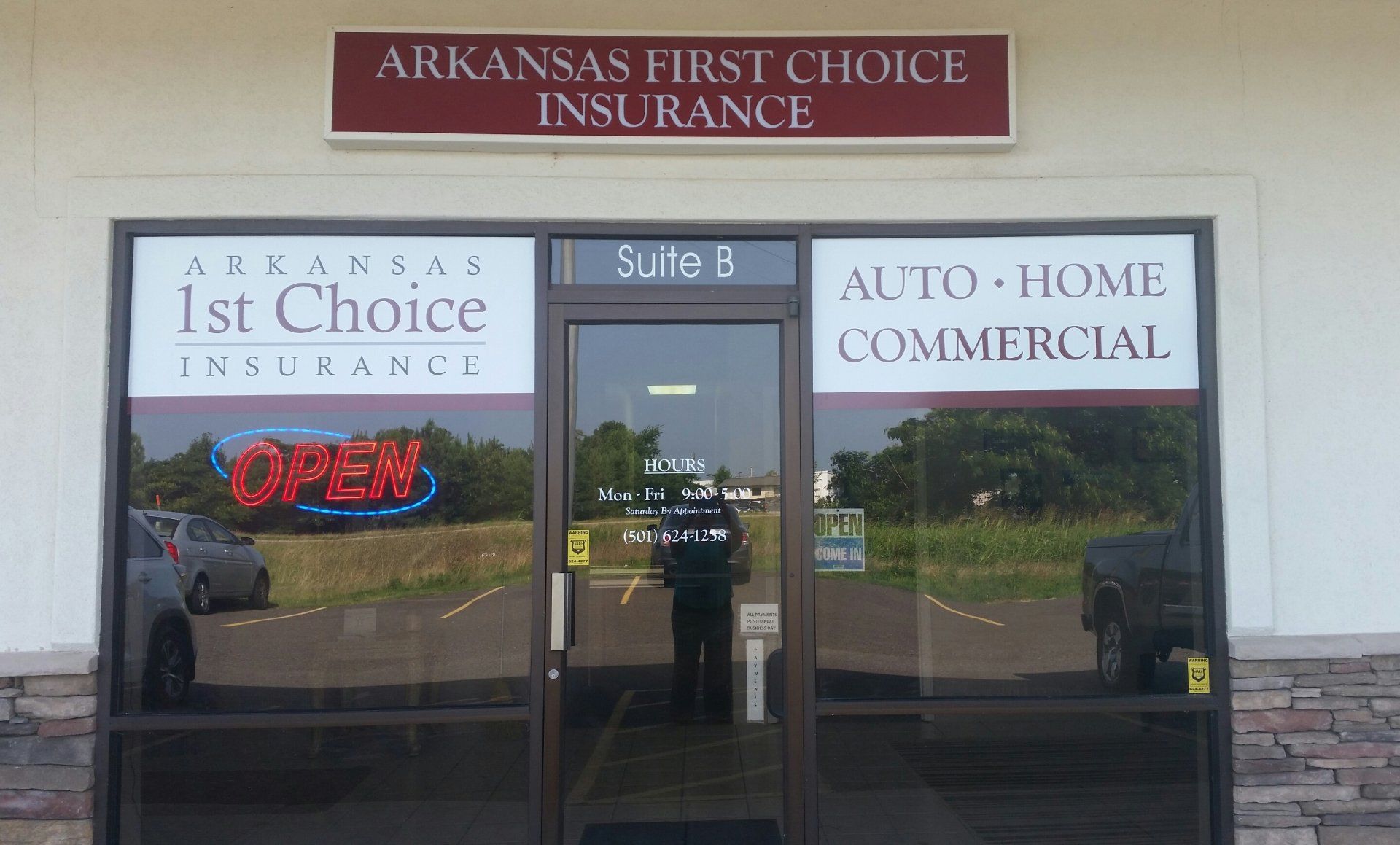 Arkansas 1st Choice Insurance storefront  in Hot Springs Arkansas with red and white signage and an “OPEN” neon sign.