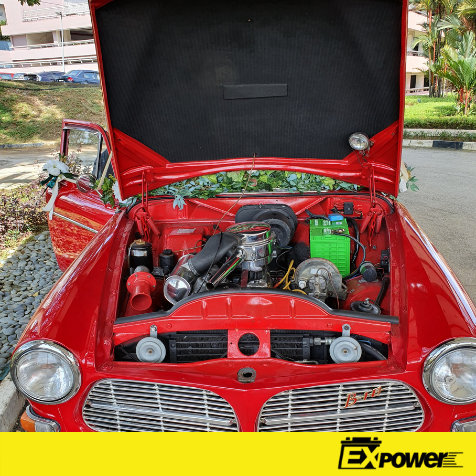 Red vintage car with hood open, showing engine bay and chrome headlights.