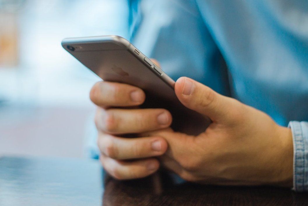 Hands holding a smartphone with a blurred blue background