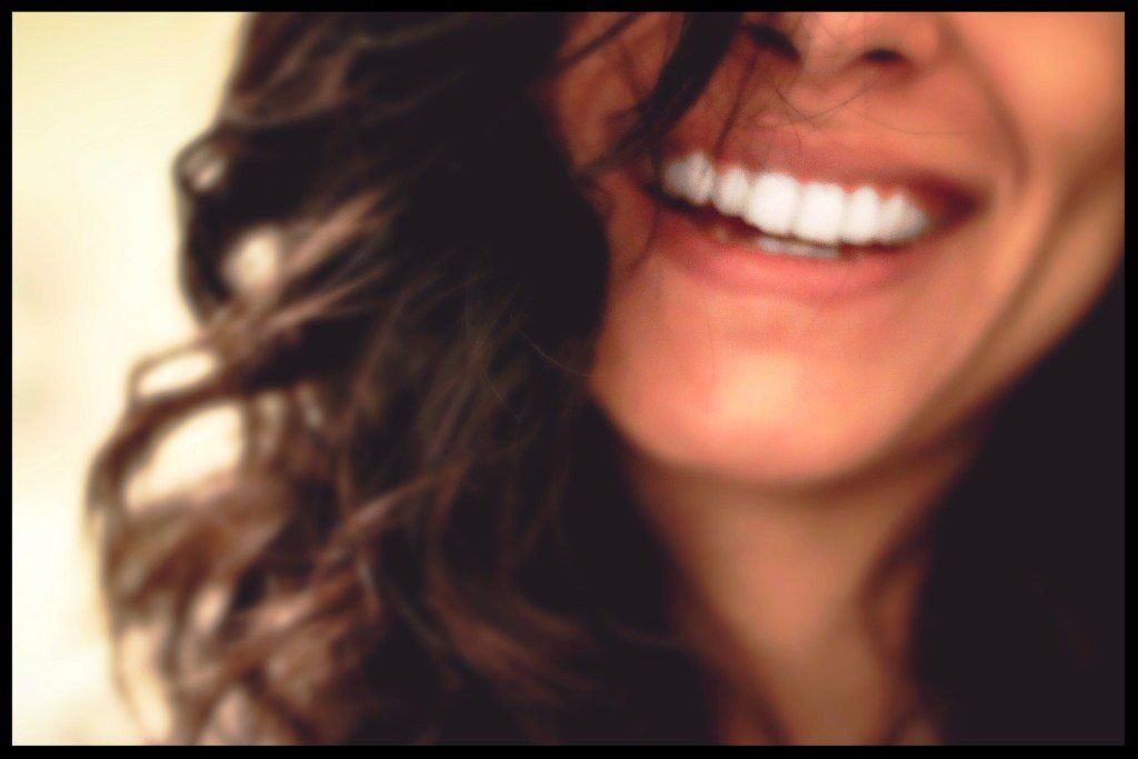 Smiling woman with curly brown hair, showing white teeth.