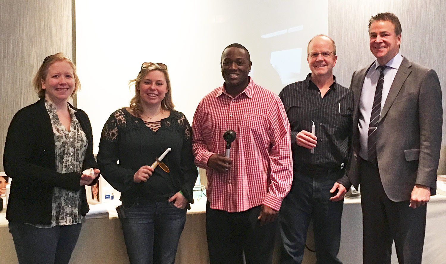Group of five people smiling at a conference, holding items and posing for a photo.