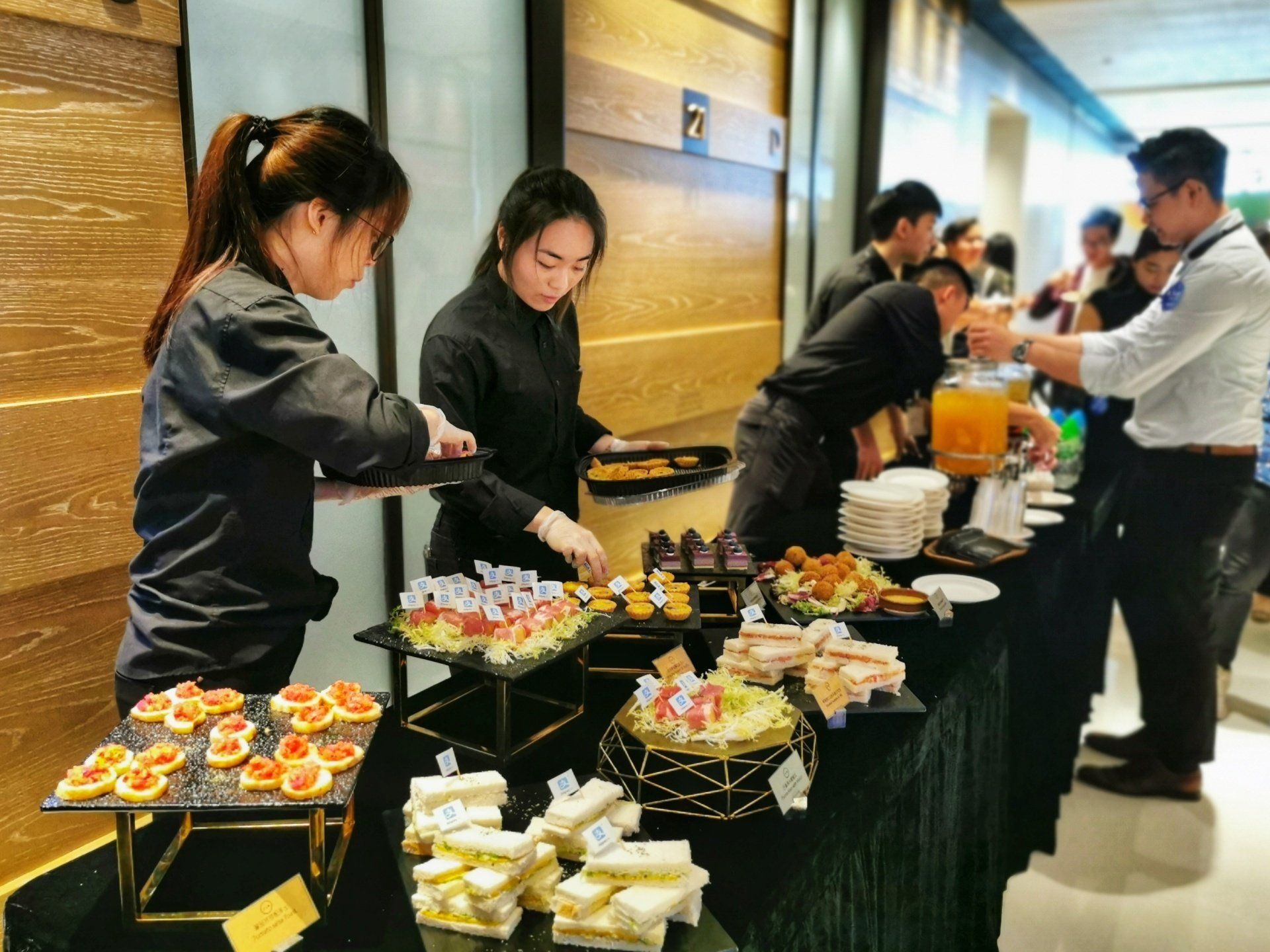 Catering table with staff serving appetizers and drinks to guests at an event.