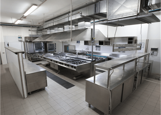 Commercial kitchen with stainless steel appliances and ventilation hoods.
