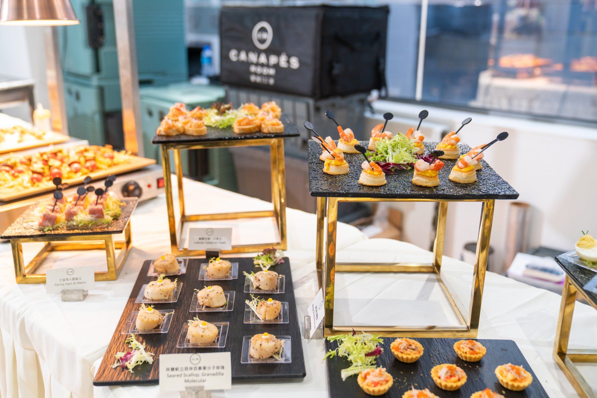 Buffet table with canapés on black slate platters, gold stands.
