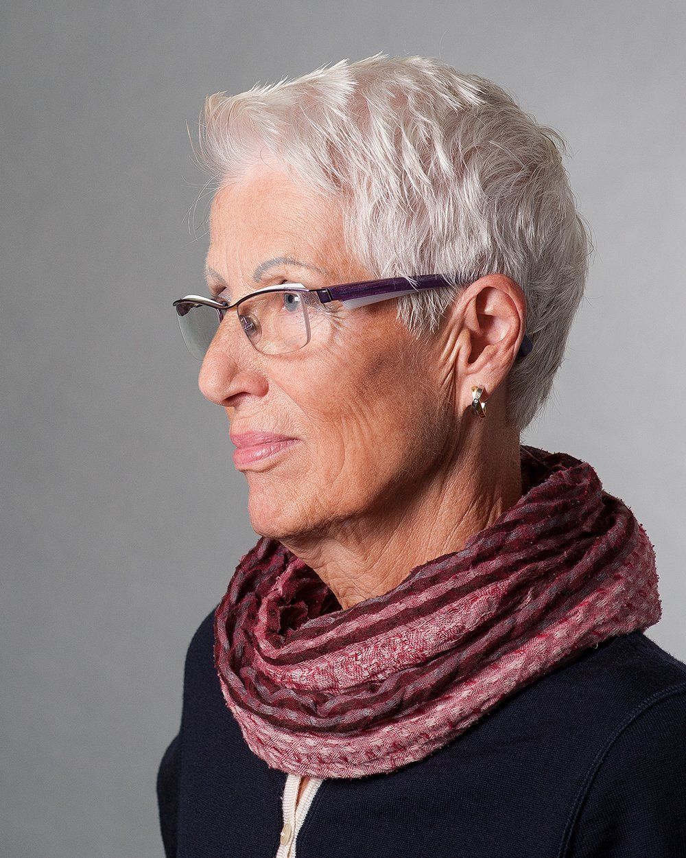 Die Frau trägt eine Brille und einen Schal um den Hals.