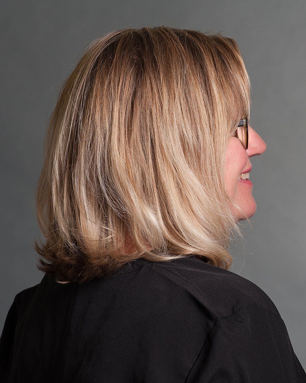 Eine Frau mit blonden Haaren und Brille trägt ein schwarzes Hemd.