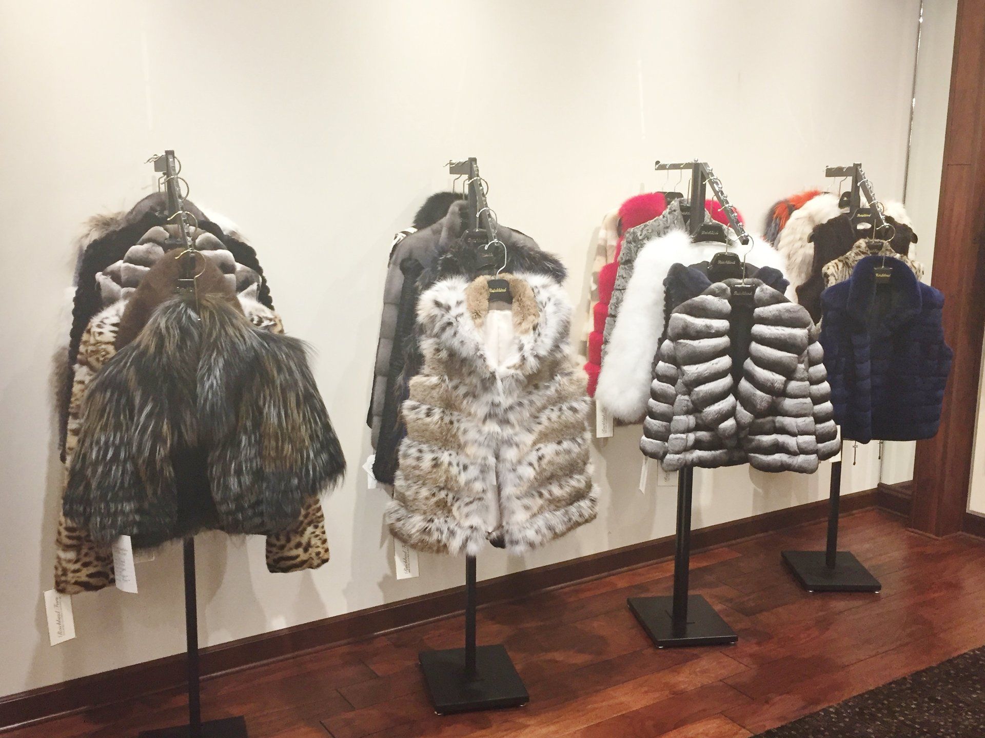 A row of fur coats hanging on racks in a room.