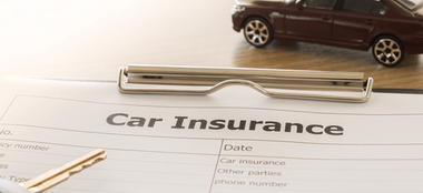 a clipboard with a car insurance form and a pen on it .