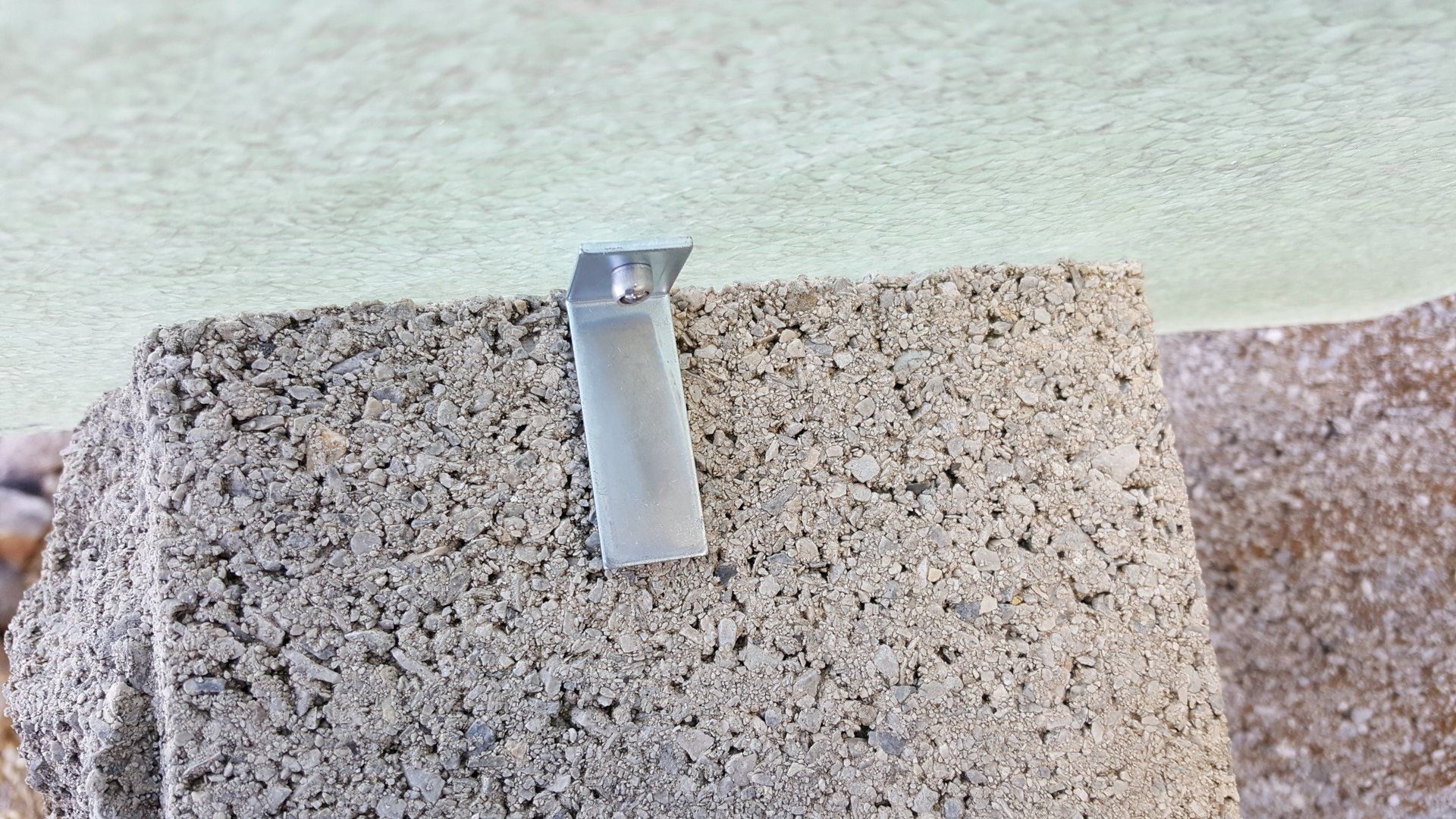 A piece of concrete with a metal clip attached to it.