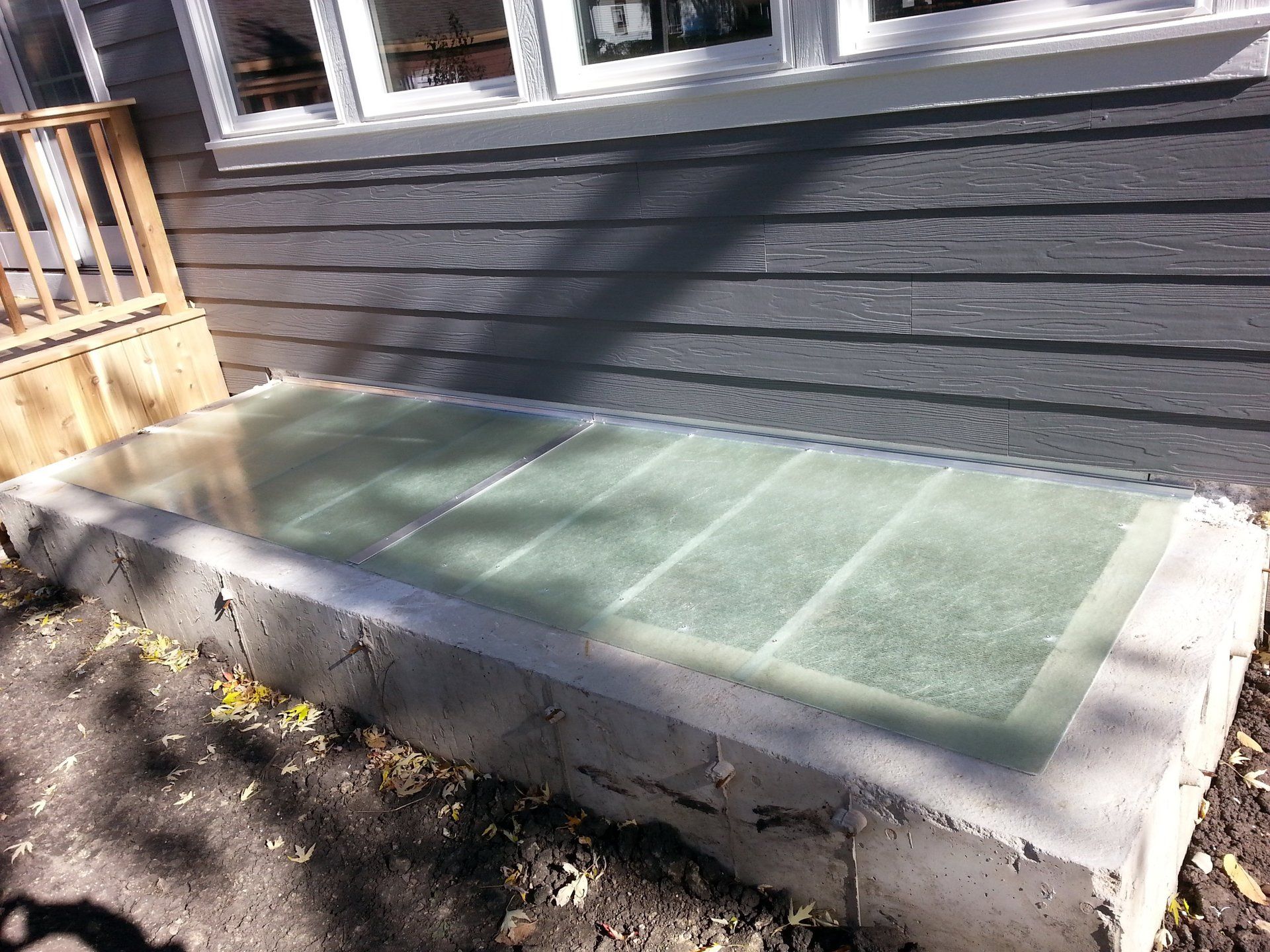 A window well is sitting on the side of a house.