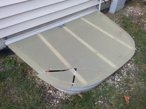 A window well with a broken glass cover on it