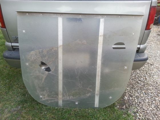 A clear plastic cover is sitting on the back of a silver truck.