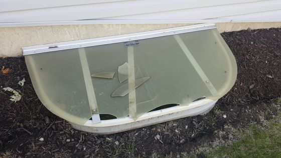 A window well with a broken glass cover on it