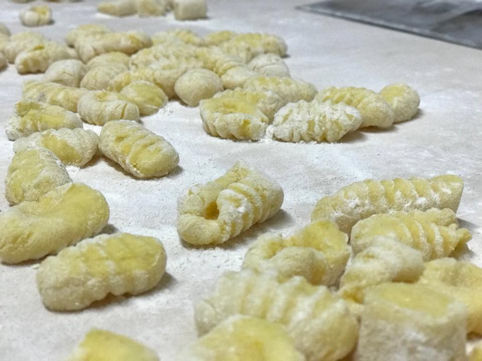Pezzi di pasta cruda per gnocchi cosparsi di farina su un piano di lavoro