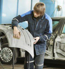 Repairman Sanding Plastic Car Bumper — Auto Repair Shop in Hyannis, MA Repairman Sanding Plastic Car Bumper — Auto Repair Shop in Hyannis, MA