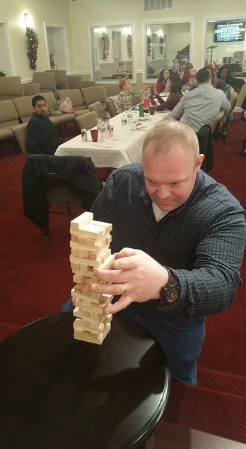 Man stacking a Jenga tower at a banquet table in a dining hall