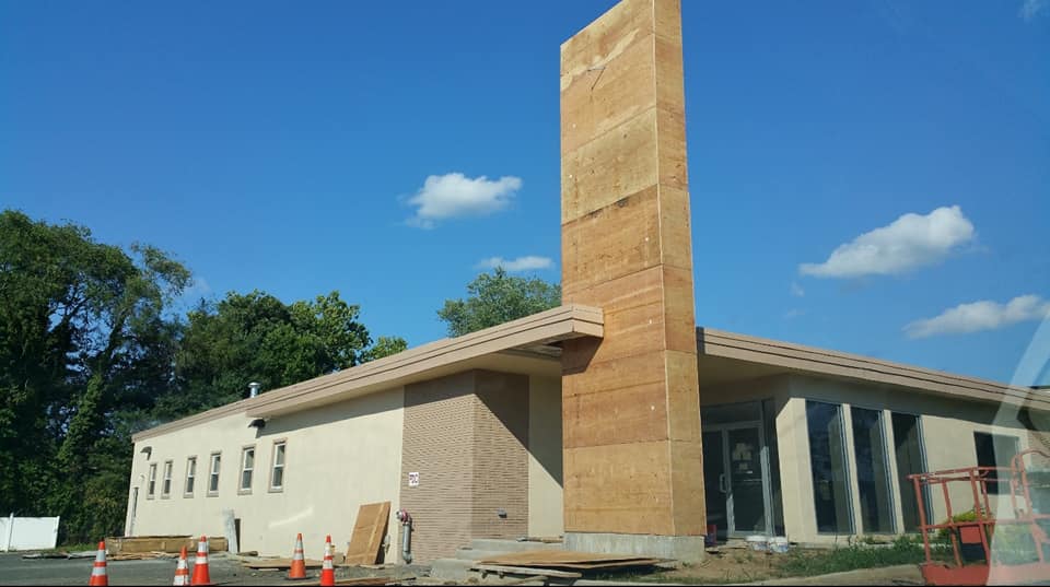 New building under construction with tall brick chimney and scaffolding under a blue sky