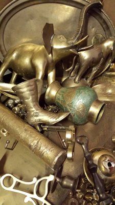 A pile of brass objects including a vase , boots , a hammer and a horse statue.