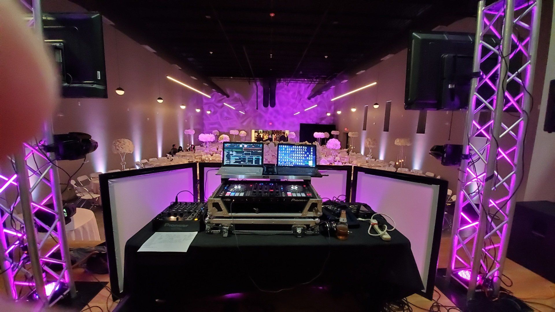 A dj set is sitting on a table in a large room with purple lights.