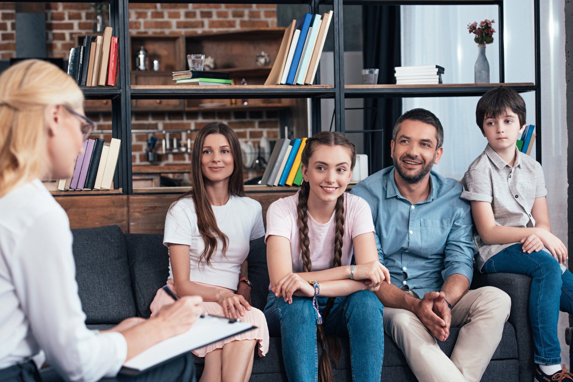 Family sitting on couch, smiling, speaking with therapist.