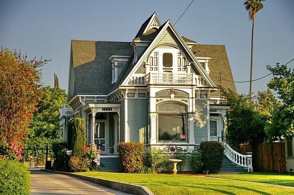 Elegant Victorian-style house in warm sunlight with intricate details, surrounded by a well-manicured lawn.