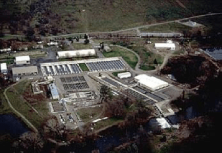 Aerial view of Coleman Fish Hatchery, water treatment facility, buildings, green patches, road, and clear skies.