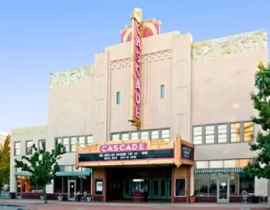 Photo of Cascade Theatre's art deco facade with vertical neon 'Cascade' sign under a clear blue sky.