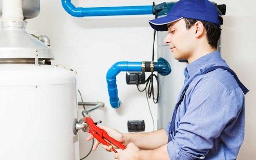 A plumber is working on a hot water heater.