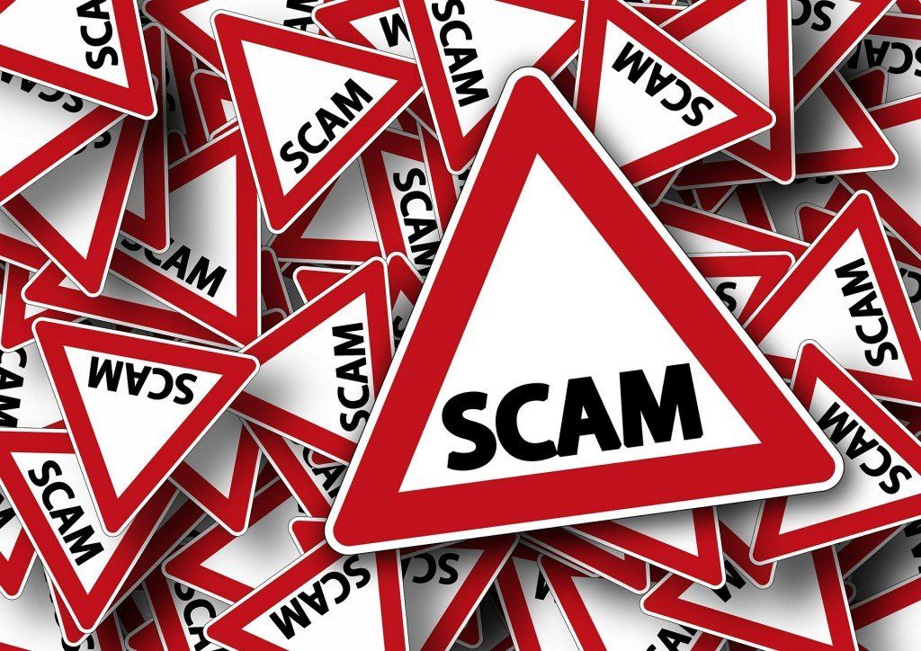 Pile of red and white warning signs with 'scam' prominently displayed, symbolizing fraud vigilance.