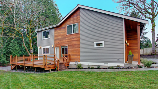 A large house with a wooden deck in front of it.