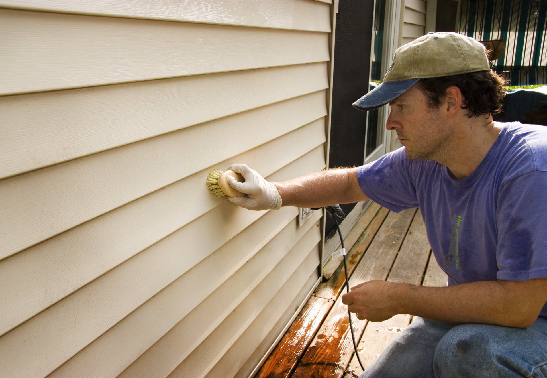 A man is cleaning the side of a house with a sponge