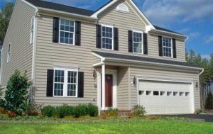 A beige house with black shutters and a white garage door