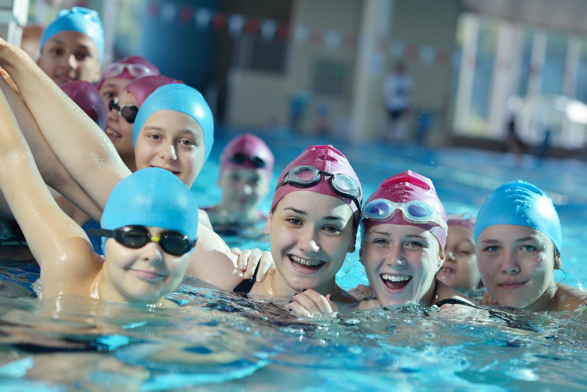 People in swim caps and goggles smile in a pool.