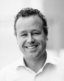 Lachende man in een wit shirt tegen een zacht vervaagde achtergrond.