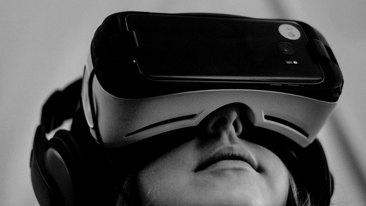 Persoon met een VR-headset op, van onderaf gezien, tegen een effen grijze achtergrond.