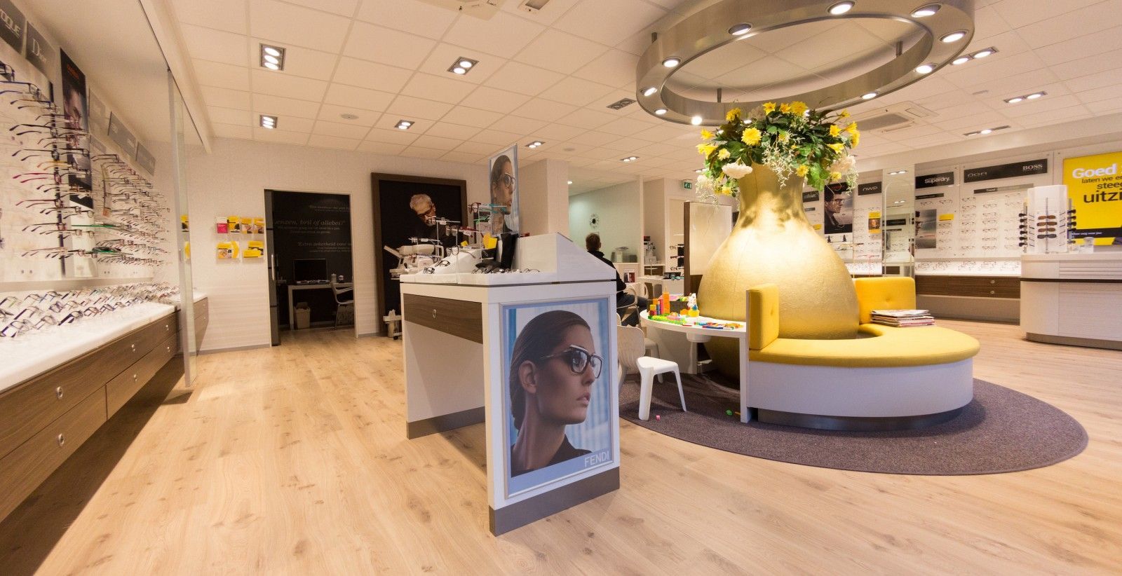 Licht en modern winkelinterieur met sieradendisplays, een centrale ronde display en een poster op een standaard.