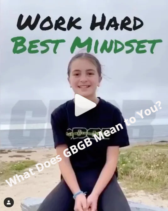 a girl is sitting in front of a sign that says work hard best mindset