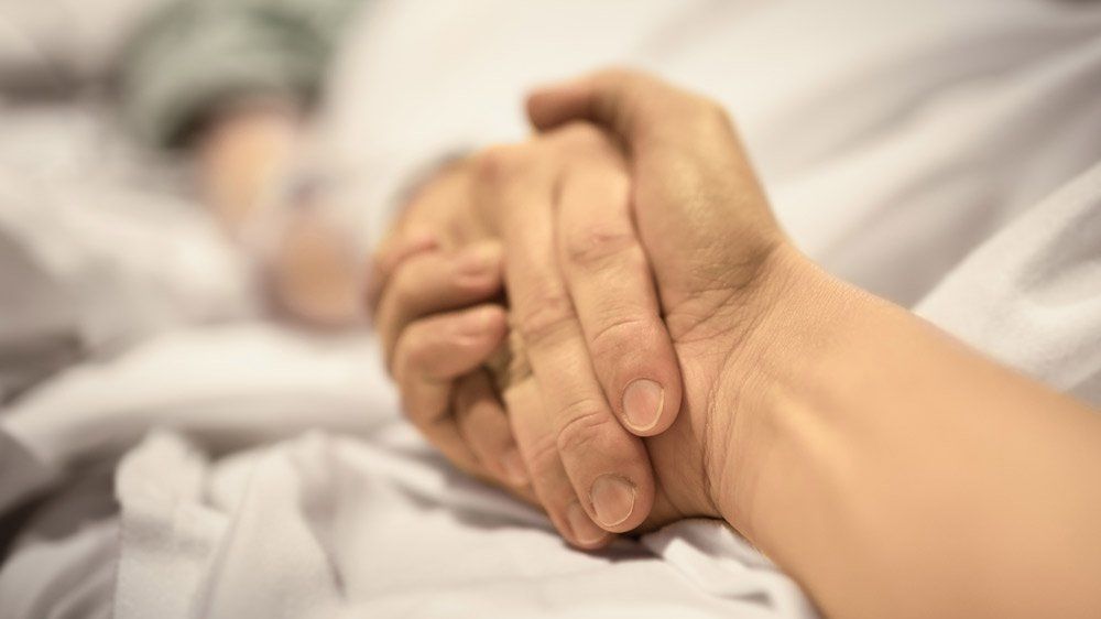 Man Holding Hand of Woman in The Hospital — Summerville, SC — Shepherd Law Firm, LLC