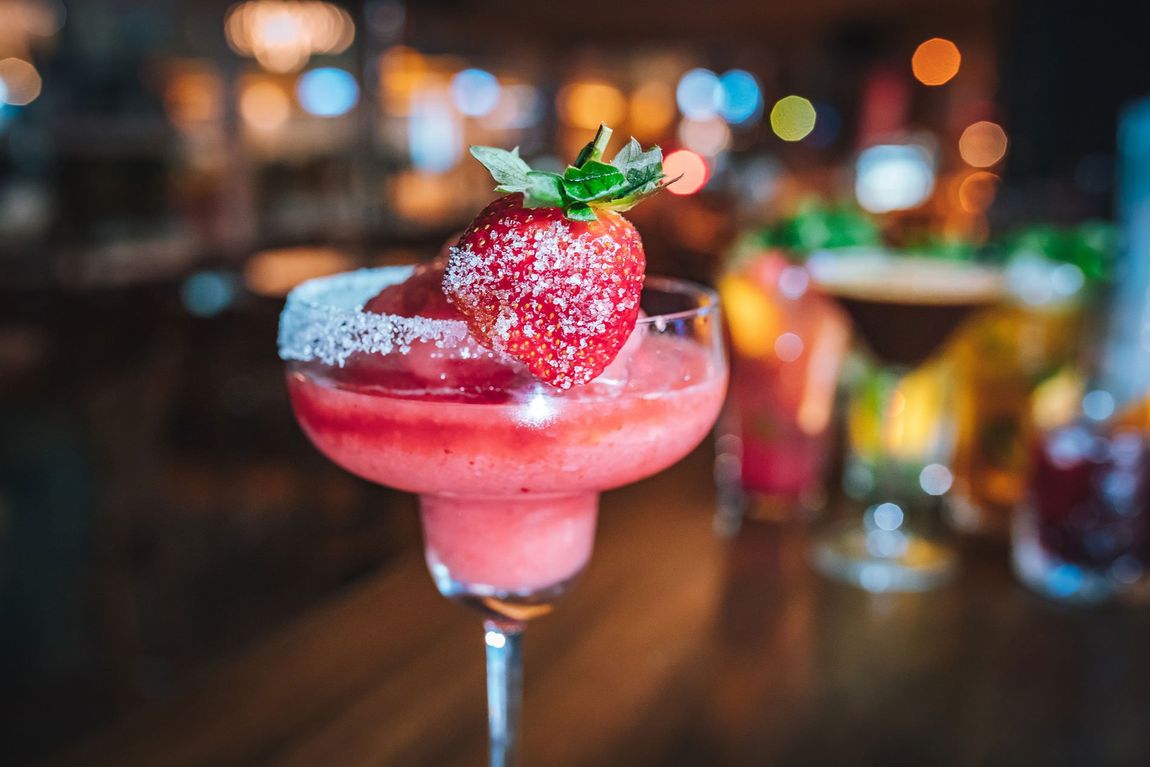 Pink Fresh colorful exotic alcoholic frozen cocktail with strawberry in the bar. Colorful pink Soft drink with strawberry on the bar desk