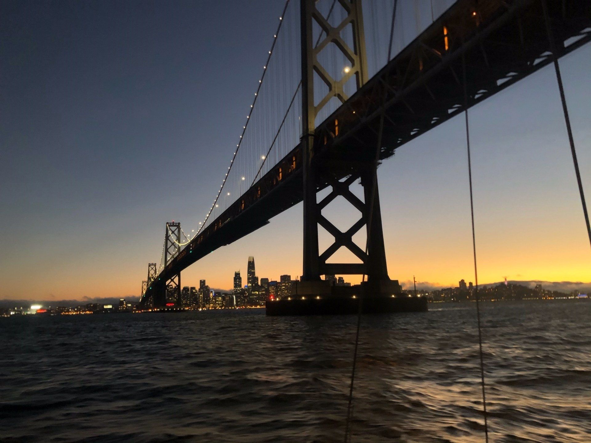 The Bay Bridge lit up at sunset with san Francisco in the background. 