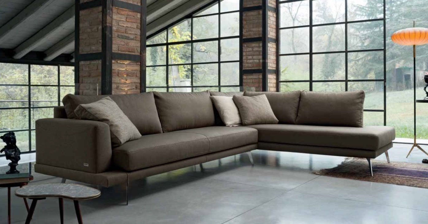 Divano componibile moderno marrone in una stanza luminosa con ampie finestre.