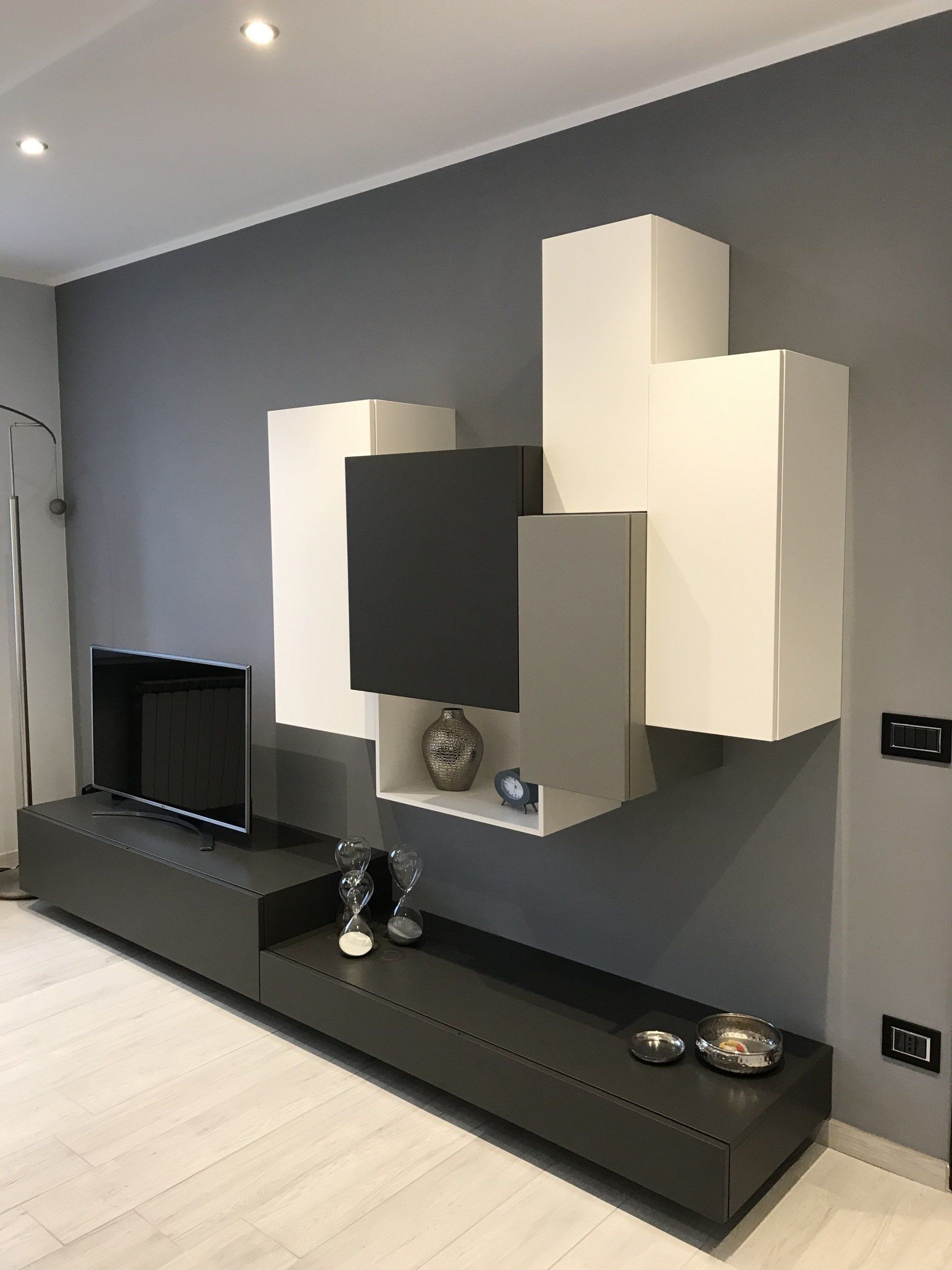 Moderna parete attrezzata grigia e bianca con TV e oggetti decorativi su una parete grigia.